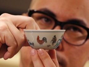 Nicolas Chow, Asia Deputy Chairman of Sotheby's International Head of Chinese Ceramics and Works of Art, poses with the Meiyintang Chenghua "Chicken Cup" in Hong Kong March 12, 2014.  (REUTERS/Bobby Yip)