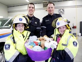 Courtney Fleming, right, along with her friend Chloe Loft, shows off the tub of stuffed animals she has donated to the Hastings-Quinte Paramedic Services, for paramedics to give to children who need to use the ambulance service. Shown in back are paramedics Rob Woollard and Tony Haker.
