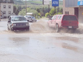 The Pat's Creek culvert overflowed on Thursday June 27, 2013 shortly after 5 pm sending water into Peace River's downtown core. Within minutes, the Peace River's downtown core was flooded with water and emergency crews quickly responded, eventually blocking off the downtown to residents. Pictured is the sight outside of ATB Financial on 100 Avenue as commuters experience the flooding on their drive home. The culvert collapsed from an overflow of water and debris.
LOGAN CLOW/PEACE RIVER RECORD-GAZETTE/QMI AGENCY