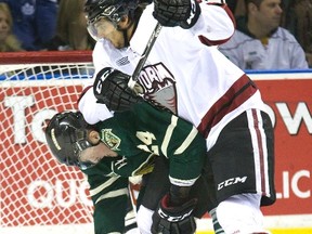 Guelph Storm defenceman Phil Baltisberger tries to clear London Knight Michael McCarron from in front of his net during OHL action in in London, Ont. on Tuesday April 8, 2014. (DEREK RUTTAN/The London Free Press/QMI Agency)