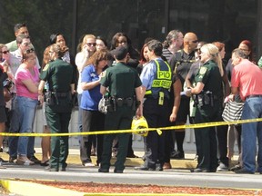 Parents and onlookers speak to police officers after a vehicle crashed into a child care center in Winter Park, Florida April 9, 2014.  Rescue officials say 12 people, including 11 children, were injured when a car crashed into a Goldenrod Road day care center.  REUTERS/Stephen M. Dowell/Orlando Sentinel