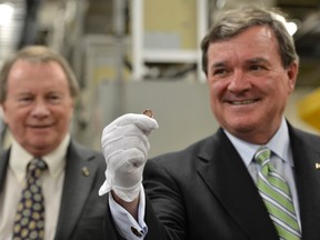 Former finance minister Jim Flaherty (right) holds the last penny produced at the Royal Canadian Mint in this May 2012 file photo. Flaherty died suddenly on Thursday. (REUTERS/Fred Greenslade)