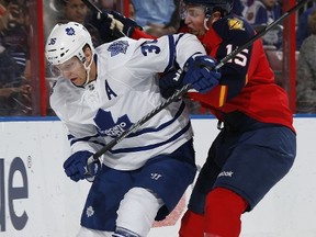 Panthers’ Drew Shore (left) checks Maple Leafs’ Carl Gunnarsson on Thursday night at the BB&T Center in Sunrise, Fla. (AFP/PHOTO)