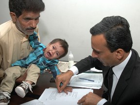 This photograph taken on April 3, 2014 shows a Pakistani lawyer taking the thumb impression from nine-month-old toddler Mohammad Musa on a bail bond in Lahore. (AFP PHOTO/STR)