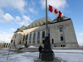 A worker raises a Canadian flag in front of the Supreme Court building in Ottawa March 21, 2014. (REUTERS/Chris Wattie)