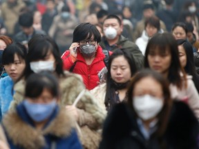 Commuters wearing masks make their way amid thick haze in the morning in Beijing in this February 26, 2014 file photo.  REUTERS/Kim Kyung-Hoon