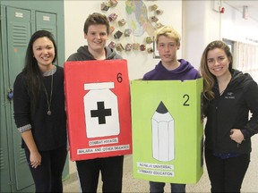 Flanked by teacher Carli Suenaga, left, and master's student Rachael Melnik-Proud, Vanier students Toban Bradlynn and Hunter Leonard wear the Millennium Project Goals boxes they wear to local schools.