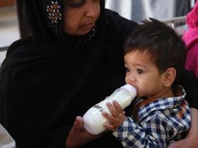 Nine-month-old baby Musa Khan drinks milk from a bottle as he sits on the lap of his grandmother Saeeda Bibi, before appearing in a court in Lahore April 12, 2014. REUTERS/Mohsin Raza