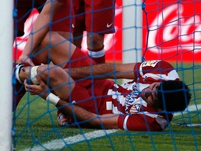 Atletico Madrid's Diego Costa reacts in pain as his teammate Jorge Resurreccion Merodio "Koke" helps him during their Spanish first division soccer match against Getafe at Coliseum Alfonso Perez stadium in Getafe, outside Madrid, April 13, 2014. (REUTERS)