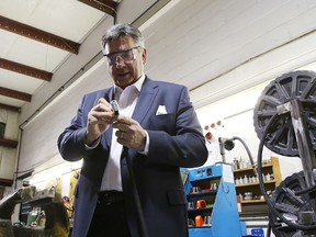 Ontario Finance Minister Charles Sousa works on a piece of industrial hose during a tour of Eastern Fluid Power in Kingston Monday. 
ELLIOT FERGUSON/THE WHIG-STANARD/QMI AGENCY