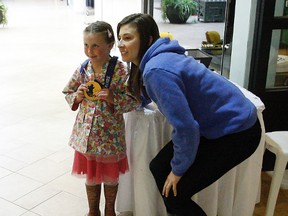 Sienna Derganc-Renette poses with the Olympic gold medal belonging to Genevieve Lacasse, right, at the Northgate Shopping Centre in North Bay on Sunday. Lacasse, a former Kingston Ice Wolves star, was signing autographs at the mall. (Jordan Ercit/QMI Agency)