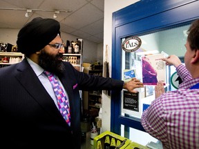 Manmeet Bhullar (left), the minister of Human Services, and Bill Robinson, and store manager Adam Koziak put up a FASD informational sign on a door at the Chateau Louis Liquor Store in Edmonton, Alta., on Monday, April 14, 2014. The AGLC are mandating that liquor stores across the province must now carry signs warning pregnant women about the dangers of fetal alcohol spectrum disorder. (FASD) Ian Kucerak/Edmonton Sun