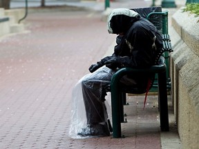 A man whose legs are covered in plastic to keep from getting rained on sleeps on a bench on the south side of the Stanley Milner Library downtown in Edmonton on Wednesday, May 25, 2011. CODIE MCLACHLAN/EDMONTON SUN