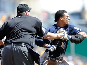 Carlos Gomez #27 of the Milwaukee Brewers is restrained by Homeplate Umpire Fieldin Culbreth during the third inning against the Pittsburgh Pirates on April 20, 2014 at PNC Park in Pittsburgh, Pennsylvania. (Joe Sargent/Getty Images/AFP)
