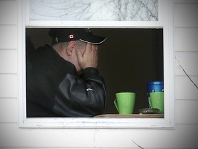 A man holds his head in his hands in a home on Dufferin Avenue near the scene where a teenage boy was found dead Saturday morning. (Brian Donogh/Winnipeg Sun/QMI Agency)