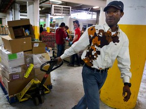 Emmanuel Kimuli carts a load of frozen goods to the freezer at the Daily Bread Food Bank in Toronto on April 21, 2014. Kimuli, volunteers at the food bank to give back to the service that has helped him since coming to Canada in 2002 as a refugee. (Dave Abel/Toronto Sun)