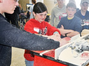 Sam Reidy squints as she runs the table saw while Simon White (right) awaits his turn during the OYAP technology days event last Tuesday, April 15 at the Mitchell & District Community Centre. KRISTINE JEAN/MITCHELL ADVOCATE