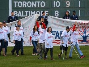 2013 Boston Marathon bombings survivors Heather Abbott (3rd L) and Jeff Bauman (2nd R) take the field during a pre-game ceremony to honor the bombings' victims, survivors and first responders before the American League MLB baseball game between the Baltimore Orioles and the Boston Red Sox at Fenway Park in Boston, Massachusetts April 20, 2014. REUTERS/Brian Snyder