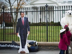 Children interact with a protester dressed as a polar bear against the Keystone XL oil pipeline project, as a cut-out of U.S. President Barack Obama is seen nearby, outside the White House in Washington, in this November 22, 2013 file photo. REUTERS/Jason Reed/Files
