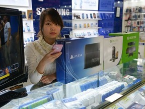 A vendor sells game consoles including Xbox One and Sony's PS4 which they say enter China through unofficial channels in a major electronics market in Shanghai on Jan. 8, 2014.  (AFP PHOTO/Peter Parks)