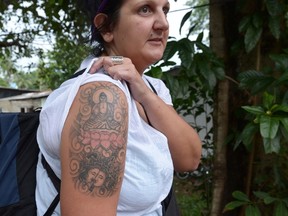 British tourist Naomi Coleman poses for a photograph to display a tattoo of the Buddha on her upper arm, after she was arrested at Sri Lanka's main international airport and later ordered with deportation for having a tattoo of the Buddha, in Colombo on April 22, 2014. (AFP PHOTO/LAKRUWAN WANNIARACHCHI)
