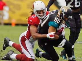 Cardinals receiver Larry Fitzgerald (left) tackles Jaguars linebacker Russell Allen during NFL action in Jacksonville, Fla. on Nov. 17, 2013. Allen retired Tuesday after suffering an on-field stroke last season. (Phil Sears/USA TODAY Sports/Files)
