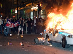 Fans watch a burning police car after a playoff game between the Bruins and Canadiens in Montreal, Tuesday, April 22, 2008. (QMI Agency/Files)
