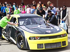 Alex Tagliani, right, pushes out his race car for a photo op with students during a discussion on the seriousness of food allergies at St. Matthews Elementary School. (Codie McLachlan, Edmonton Sun)