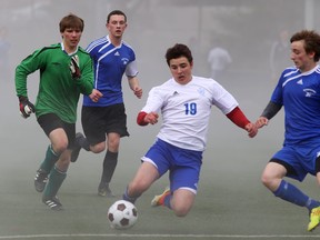 Kingston Blues' Jayson Huang (19) slides for the ball during Tuesday  afternoon's season-opening Kingston Area senior boys soccer game against Marie-Rivier at Tindall Field. The Blues won the game 5-0. (Elliot Ferguson/The Whig-Standard)