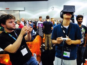 Software designer Julian Kantor (L), who created "The Recital", takes a picture of Jonathan Feng using the Oculus Rift virtual reality headset to experience his program during E3 in Los Angeles, Calif., in this June 12, 2013 file photo. Facebook Inc will acquire two-year-old Oculus VR Inc, a maker of virtual-reality glasses for gaming, for $2 billion, buying its way into the fast-growing wearable devices arena with its first-ever hardware deal. On March 25, 2014, Facebook said virtual-reality technology could emerge as the next social and communications platform.   REUTERS/Gus Ruelas/Files