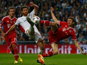 Real Madrid's Xabi Alonso kicks the ball in front of Bayern Munich's Mario Goetze (left) and Thomas Mueller during their Champions League semifinal first leg match at Santiago Bernabeu stadium in Madrid, April 23, 2014. (REUTERS/Michael Dalder)