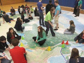 Bayridge Secondary School teacher Brenda Scarlett, standing at centre, works with her students on a giant map of Canada's national parks during an environmental summit at the high school on Wednesday.
Michael Lea The Whig-Standard