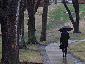 A man walks with an umbrella outside the Alberta Legislature in Edmonton, Alta., on Wednesday, April 23, 2014. Rain fell in the Capital Region all day. Ian Kucerak/Edmonton Sun