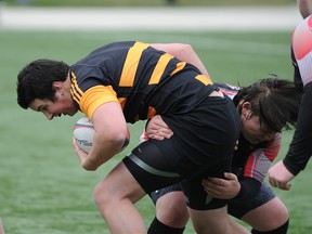 Ball carrier Kenton Carmody of the La Salle Black Knights is wrapped up by Josh Jobin of the Queen Elizabeth Raiders during a Kingston Area senior boys rugby game at Nixon Field on Wednesday. (Justin Greaves/For The Whig-Standard)