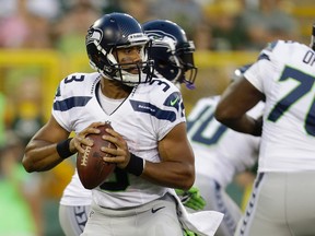 Russell Wilson #3 of the Seattle Seahawks drops back to pass during the game against the Green Bay Packers at Lambeau Field on August 23, 2013 in Green Bay, Wisconsin. The Packers will travel to Seattle to open the 2014 season. (Mike McGinnis/Getty Images/AFP)