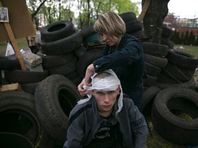 A woman bandages the head of a pro-Russian activist injured outside the Mariupol town hall, East Ukraine April 24, 2014. The Mariupol police said officers were still conducting investigations in the building after breaking up a fight overnight when separatists occupying the city hall were attacked inside by about 30 unidentified men armed with clubs. REUTERS/Baz Ratner