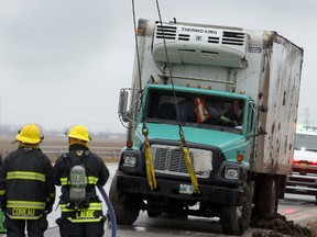 Winnipeg firefighters watch as a 5 ton is righted following a rollover at Highway 7 and the Perimeter in Winnipeg, Man. Thursday April 24, 2014. The extent of injuries to the driver is unknown. (Brian Donogh/Winnipeg Sun)