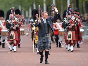 Former British cyclist Sir Chris Hoy (C) carries the Commonwealth Games baton on the Mall in London.