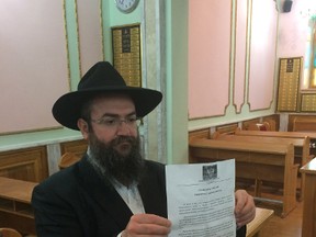 A Rabbi holds the actual document in question, in the Donetsk synagogue.