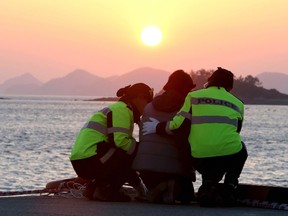 Policewomen comfort a family member of missing passengers onboard the capsized passenger ship Sewol, as she waits for news from a search and rescue operation team, during sunset at a port in Jindo April 30, 2014. REUTERS/Yonhap