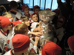 The Nepean Raiders Peewee Minor B team gather around the Stanley Cup Wednesday.