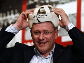 Canada's Prime Minister Stephen Harper tries on a vintage helmet during a tour of an ice hockey museum in Whitehorse, Yukon on August 25, 2011. (REUTERS/Chris Wattie)