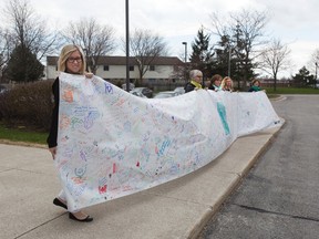 Bailey Gandy, left, Susanne McPhail, Lisa Pierce, Dani Bartlett and Shelley Yeo hold a 10-metre long banner covered in women?s signatures from across the country in London Thursday. (DEREK RUTTAN/The London Free Press)