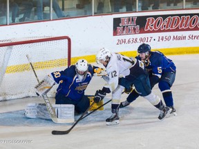 Dylan Hollman of the Saints tries to score on Blues goalie Byron Spriggs as Ryan Bittner of the Blues defends on Thursday night at the Western Canada Cup.