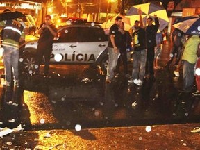 The wrapped body (out of picture) of Paulo Ricardo Silva, 26, a soccer fan who was killed in clashes between fans, lies on a street as policemen (back) stand nearby outside Arruda stadium after a soccer match between Brazilian soccer teams Parana and Santa Cruz, in Recife, northeastern Brazil May 3, 2014. (REUTERS)