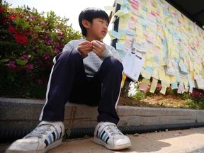 A boy sits next to a board with messages written for victims of sunken passenger ship Sewol, outside the official memorial altar in Ansan May 2, 2014.   REUTERS/Kim Hong-Ji