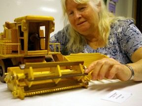 Doreen Smith admires a model combine carved by Ken Greenslade and on show at the 28th annual Appreciation of the Arts, Wednesday through Saturday at the Church of Jesus Christ of Latter Day Saints, Elm St. and Park Ave. (Eric Bunnell, Times-Journal)