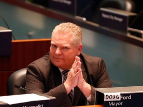 Councillor Doug Ford sits in Mayor Rob Ford's chair at a meeting of Toronto council on Tuesday, May 6, 2014, the first with Mayor Rob Ford in rehab, and Councillor Giorgio Mammoliti taped Doug's name over Rob's. (Michael Peake/Toronto Sun)