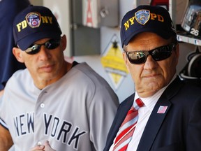 New York Yankees manager Joe Girardi stands with former New York Yankees manager Joe Torre in the dugout as they wear FDNY and NYPD baseball caps on the 10th anniversary of the 9/11 attacks on September 11, 2011 (REUTERS/Danny Moloshok)