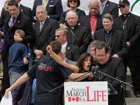 A topless pro-choice protester tries to disrupt Gerald Lacroix, Archbishop of Quebec, during Thursday's National March for Life anti-abortion rally. Tens of thousands of people gathered for the march which started on Parliament Hill in Ottawa.  (Tony Caldwell/QMI Agency)